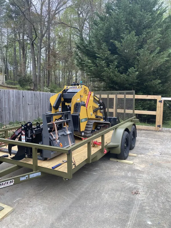Vermeer S925TX loaded on a trailer with grapple and pallet forks